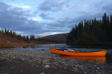 Canoe on the river, with a dusting of snow in the background
